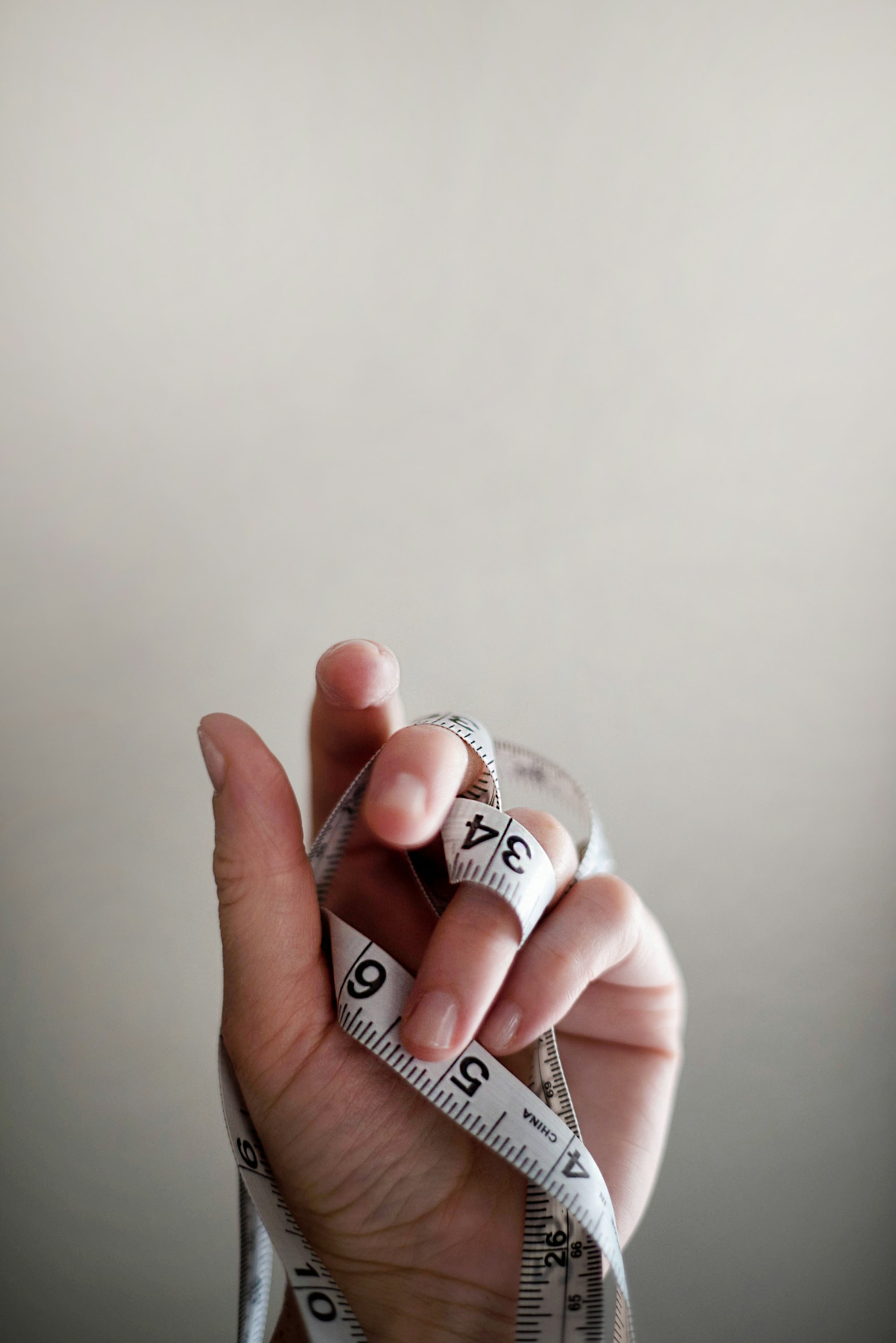 A hand holding a tailor's measuring tape
