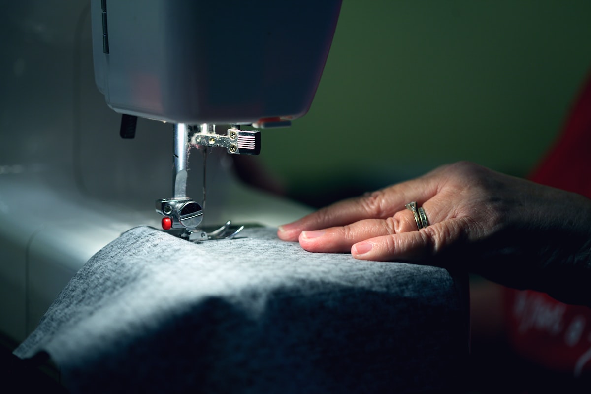 Close-up of hands guiding fabric through a sewing machine